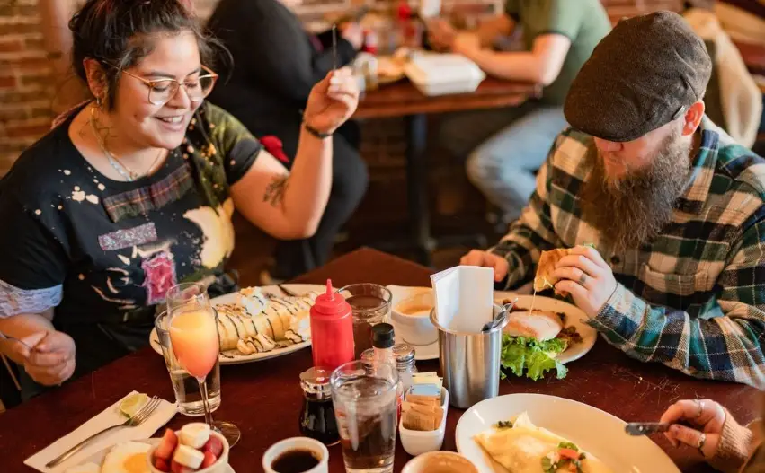 A group of people sitting at a table eating food.